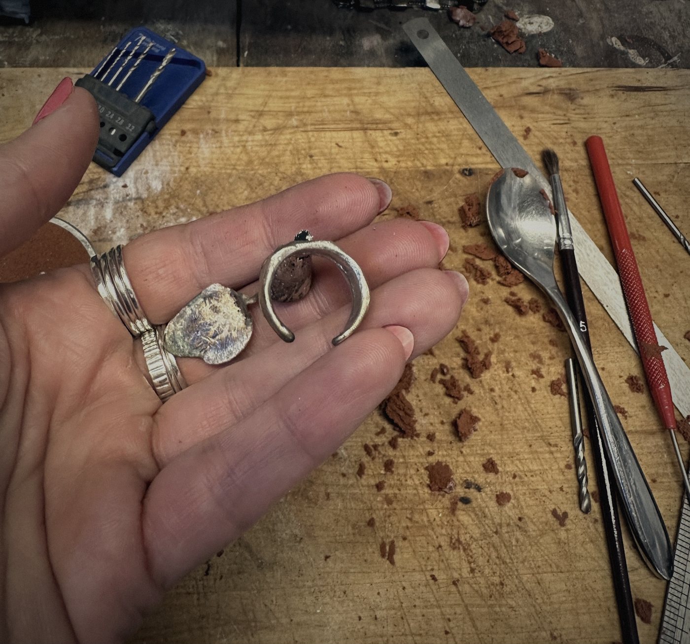 Ruwe zilveren ringen net uit de gietvorm in de hand, op de werkbank