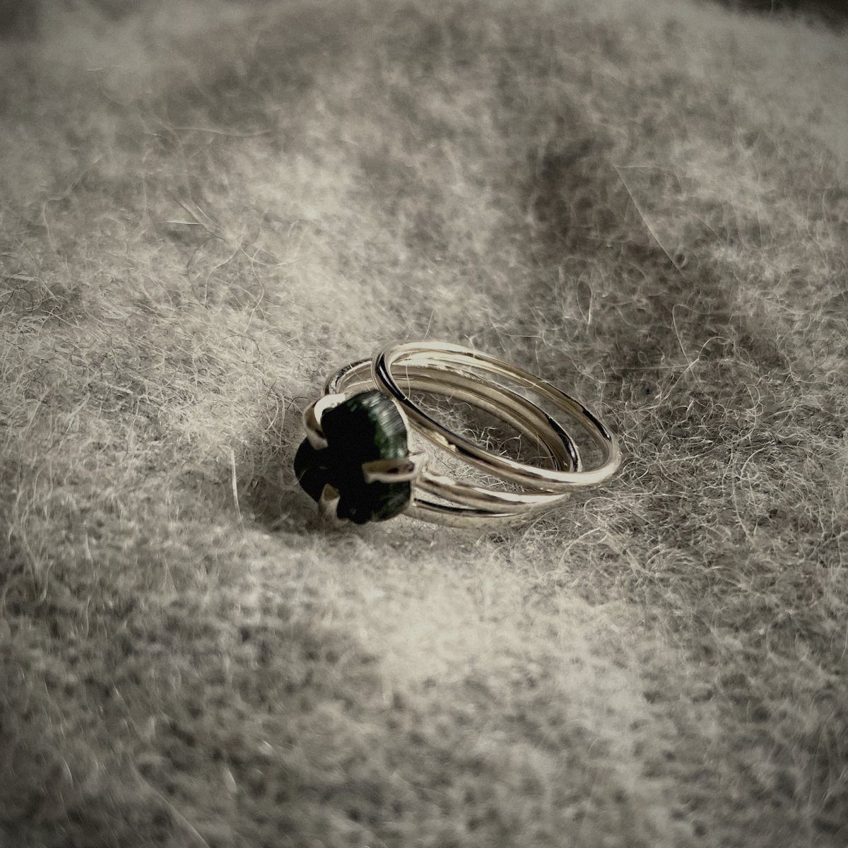 Zilveren ring met een donkere saffier in een griffenzetting op wol